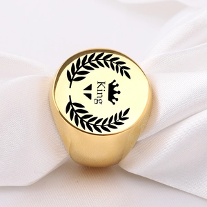 Macro shot of gold polished signet ring with King crown emblem on white silk