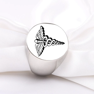 Close-up of a stainless steel signet ring featuring an engraved caduceus symbol on silk