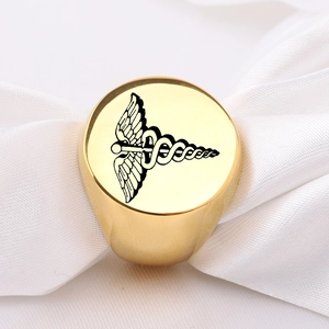 Detailed macro view of a gold-polished ring featuring a black double snake caduceus logo
