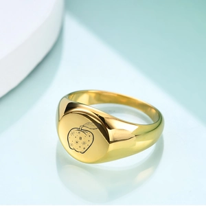 Macro shot of polished 18K gold stainless steel signet ring with engraved apple and stars