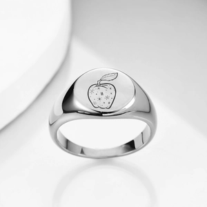 Macro view of polished silver signet ring featuring a laser-engraved apple and star design