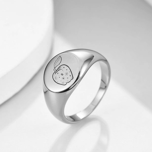 Detailed macro view of silver apple ring with starburst engraving on smooth oval band