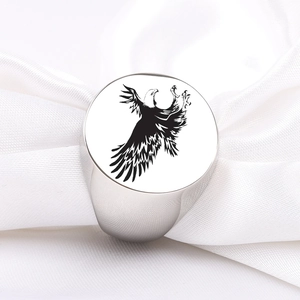 Macro shot of silver stainless steel signet ring with a black eagle engraving on white silk