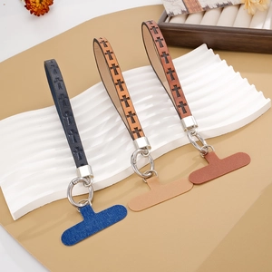Cross-patterned leather phone wrist straps in navy, wood, and reddish-brown colors