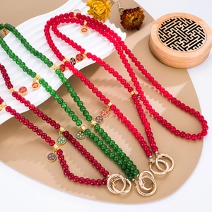Detail of colorful beaded cross-body straps with enamel charms and large golden buckles