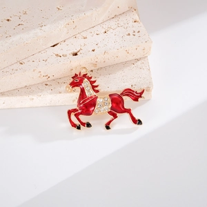 Détail d'un pendentif cheval en émail rouge avec bordure dorée et strass brillants
