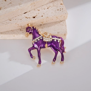 Détail d'une breloque cheval en émail violet avec strass brillants sur fond de pierre