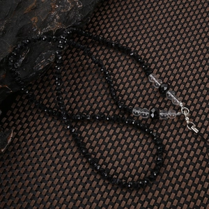 Macro shot of black faceted crystal beads with silver metal clasp on a textured background