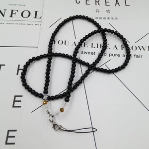 Close-up of black beaded universal phone lanyard with silver lobster clasp on magazine base