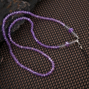 Detailed macro view of faceted purple crystal beads with transparent accents and metal clasp