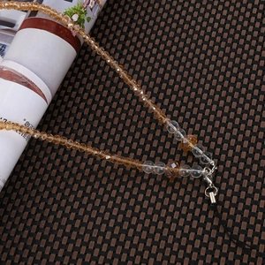 Detail of amber and clear multifaceted crystal beads on a phone charm with metal clasp