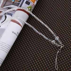 Macro shot of clear faceted crystal beads with silver lobster clasp on a woven mat
