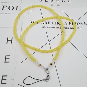 Macro detail of yellow beaded crystal phone lanyard with gold accents and silver clasp