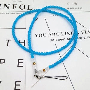 Detail of blue crystal bead phone lanyard with silver lobster clasp on a stylish magazine