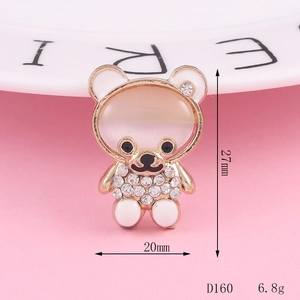 Sparkling rhinestone bear charm with cat eye stone and enamel details on pink background