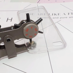 Close-up of multifunctional rotary hole punch tool piercing a transparent TPU phone case