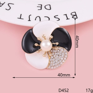 Vue macro de broche camélia avec pétales en émail noir et blanc et perle centrale