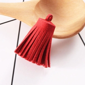 Close-up of 3cm red faux suede tassel with semi-circular ring on a wooden prop