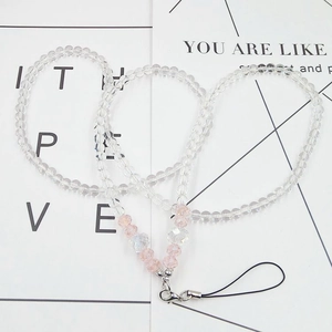 Detailed macro view of crystal beads and pink stones on a phone lanyard with silver clasp
