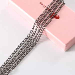 Detail of gunmetal grey chain links draped over a pink gift box for DIY accessories
