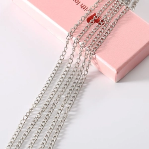 Close-up of fine silver metal fringe chains draped over a pink gift box for DIY jewelry making