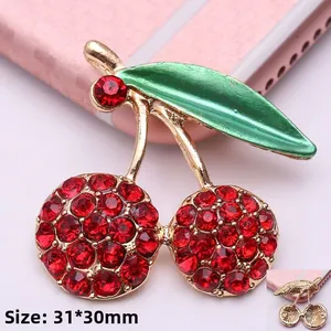 Vista detallada del dije de cereza con pedrería roja y esmalte verde de 31x30mm