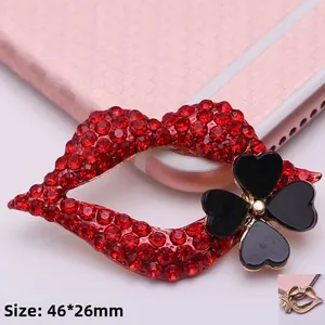Detalle de broche de labios con diamantes rojos, trébol negro y dimensiones