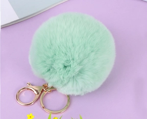 Détail du pompon en fausse fourrure vert menthe avec attache porte-clés dorée polie