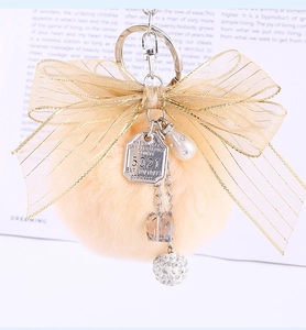 Macro detail of plush faux fur pompom with golden mesh bow and luxury metal charms