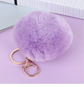 Détail du porte-clés pompon en fausse fourrure violette avec fermoir mousqueton or rose