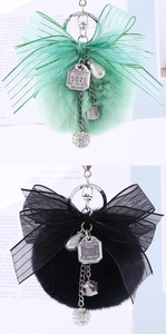 Close-up of fluffy faux rabbit fur pompom keychain with mesh bow and vintage metal tags