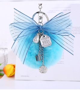 Close-up of sky blue faux fur pompom and striped chiffon bow keychain with pearl detail