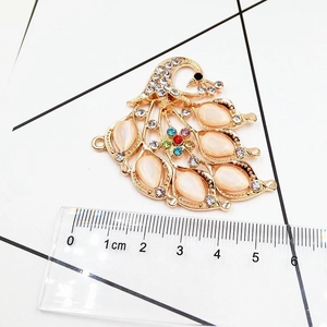 Detailed view of golden peacock pendant with colorful stones measuring 5cm in width
