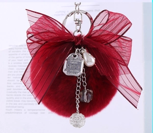 Detail view of burgundy faux rabbit fur keychain with ribbon bow and crystal charm