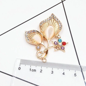 Macro shot of gold alloy flower pendant with colored crystals and beige opal inlays
