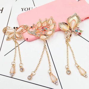 Macro view of golden butterfly and peacock charms with crystals for phone case DIY