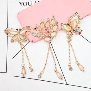 Detailed view of peacock and flower alloy charms with gold tassels and crystals