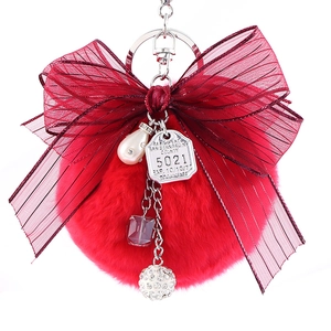 Faux rabbit fur ball keychain with large burgundy mesh bow and decorative charms