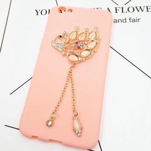 Detail of pink phone case with gold peacock ornament, rhinestones and tassel charms