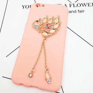 Detailed view of pink phone case with golden peacock inlay and hanging metal tassels
