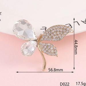 Primer plano de un broche de mariposa dorado con diamantes de imitación y cristal