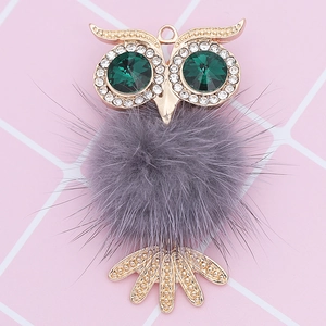 Detailed view of an owl pendant featuring green gemstone eyes and a grey faux fur body