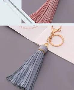 Detail view of gray and pink leather tassel keychain with golden metal lobster clasp