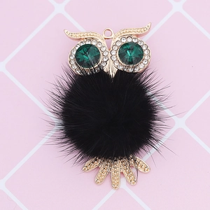 Detail of owl pendant with green rhinestone eyes and black fluffy fur ball charm