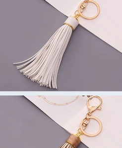Detail of white and camel leather tassel keychains with golden lobster clasps