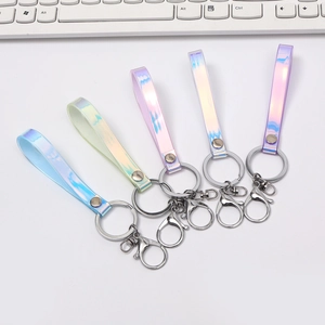 Five iridescent holographic leather keychains with silver lobster clasps on white surface