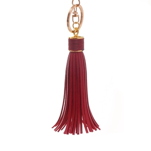 Detail of red leather tassel keychain with gold D-ring buckle and metallic finish