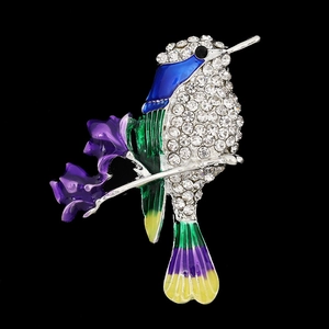 Macro shot of hummingbird brooch with colorful enamel wings and crystal rhinestones
