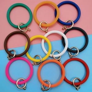 Flat lay of colorful silicone O-ring wristlets with golden spring clasps on split background