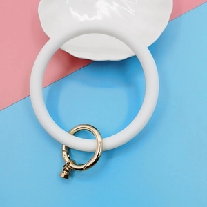 Detailed view of a white silicone ring wristlet with a golden metal spring clasp
